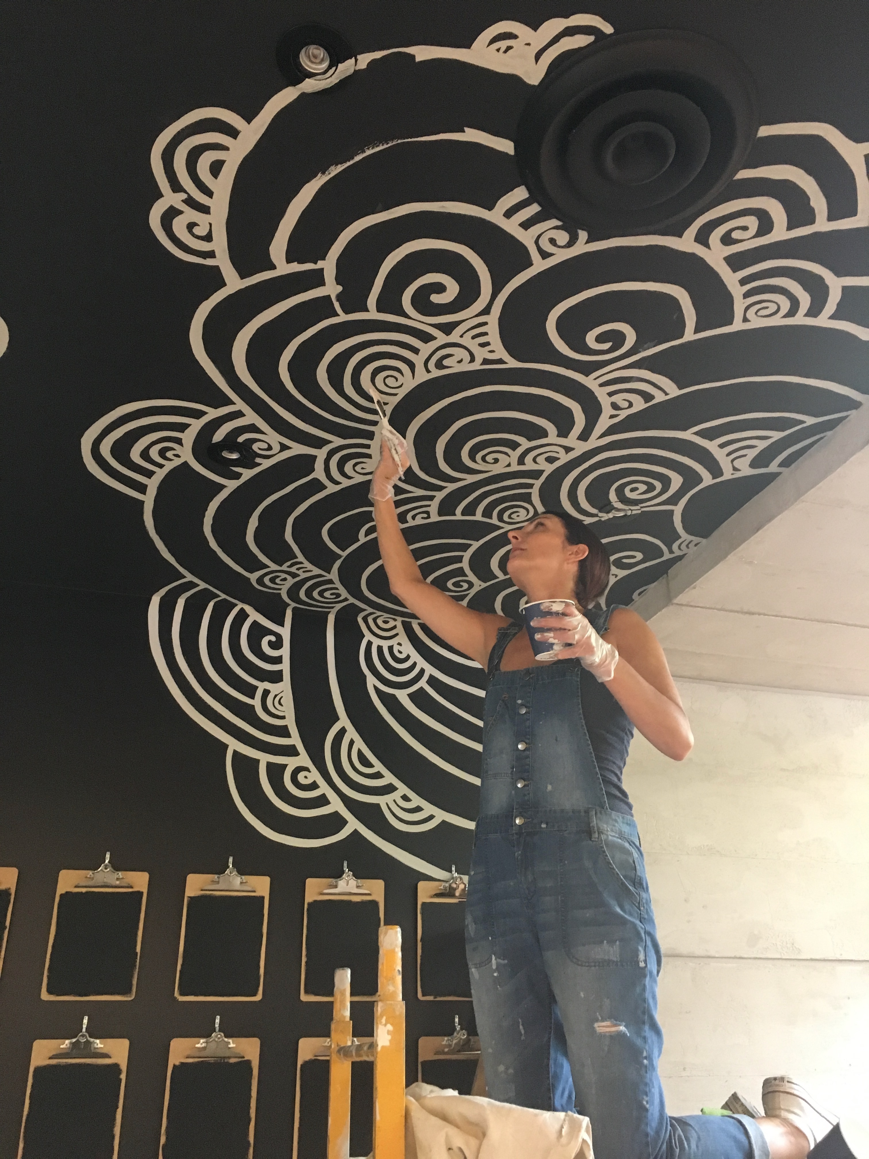 Lina hand-painting a flowing ceiling mural