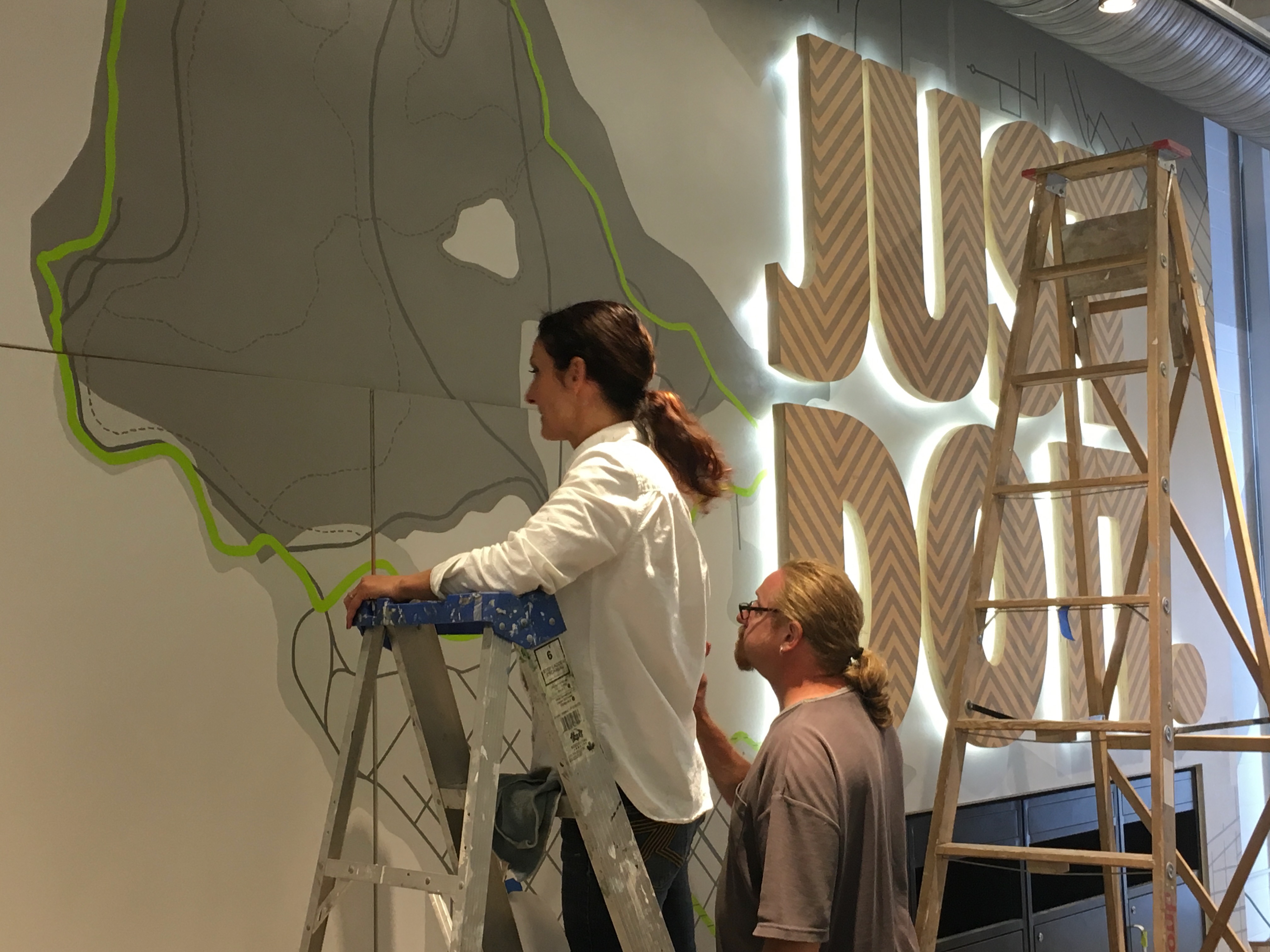 Lina and her team installing a hand-drawn Nike store wall graphic